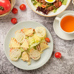 Restaurant cold caesar salad with chicken, cherry tomato, green leaves and herbs on a stone background. Food and drink concept.
