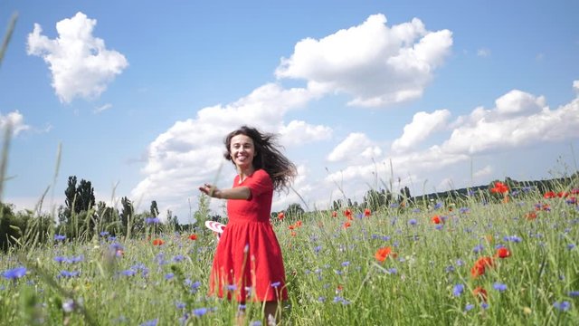 Happy young woman in red dress and big hat Enjoying Nature. Slow motion HD video Beauty Girl Outdoor walks on a poppy field. Freedom concept. Beauty Girl over Sky and Sun