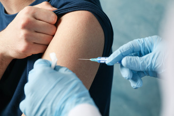 Doctor does an injection patient on blue background. Coronavirus protection. Healthcare and medical concept