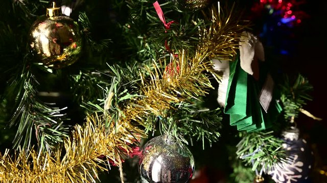 Footage with close-up and tracking shot on a Christmas tree richly decorated with colored balls and ribbons. Christmas holiday concept. Blurred indistinguishable background.