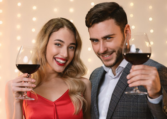 Attractive Couple Holding Glasses With Wine, Toasting And Smiling At Camera