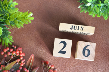 July 26, Number cube design with flower on brown lether background.