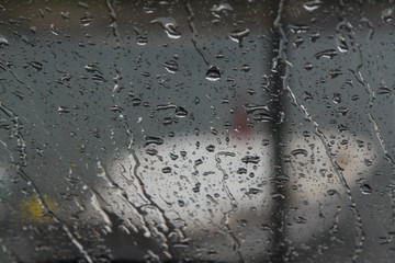 Rain drops on the glass in the spring afternoon. Close up of a window with rain drops falling down.The rain drops on household windows. Focus on rain drops. concept of sadness, frustration