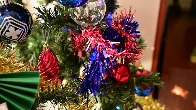 Footage with close-up and tracking shot on a Christmas tree richly decorated with colored balls and ribbons. Christmas holiday concept. Blurred indistinguishable background.