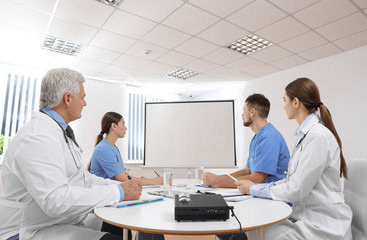 Team of doctors using video projector during conference indoors