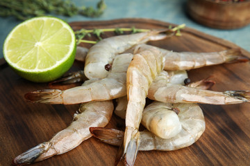 Fresh raw shrimps and lime on wooden board, closeup