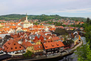Fototapeta na wymiar Vltava river flowing through the medieval village of Cesky Krumlov with a green hill at the background, in Czech Republic