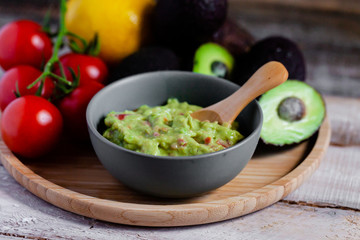 Tasty and healthy mexican snack: avocado guacamole. Homemade, served with bread stick with herbs on a wooden rustic table. Delicious and low calorie meal to share for the company. Close up, macro