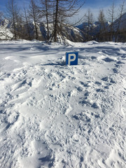Parking signpost completely submerged by snow in a mountain resort.