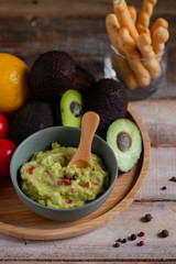 Tasty and healthy mexican snack: avocado guacamole. Homemade, served with bread stick with herbs on a wooden rustic table. Delicious and low calorie meal to share for the company. Close up, macro