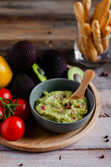 Tasty and healthy mexican snack: avocado guacamole. Homemade, served with bread stick with herbs on a wooden rustic table. Delicious and low calorie meal to share for the company. Close up, macro