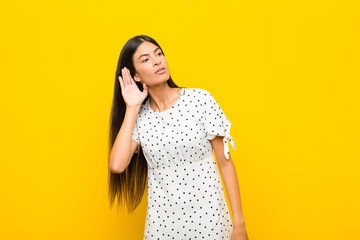 young pretty latin woman looking serious and curious, listening, trying to hear a secret...