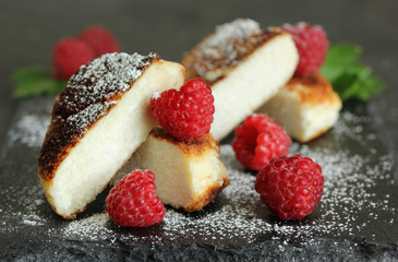 Breakfast. Cheesecakes with raspberries on a dark wooden background. Background image, copy space