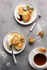 Breakfast. Cheesecakes with sour cream, jam and tea on a light background. Background image, copy space