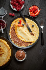 Delicious chocolate homemade pancakes on black ceramic plate