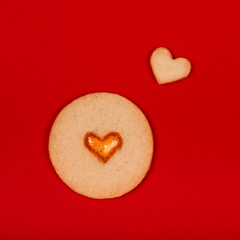 Obraz premium Cute handmade cookies in the shape of heart on red background. Concept of the Valentine's Day, surprises with love, holiday, etc. Flat lay.