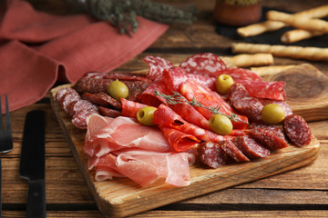 Tasty prosciutto with other delicacies served on wooden table