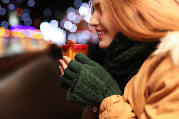 Happy woman with tasty mulled wine at winter fair