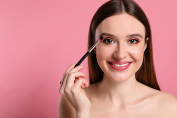 Beauty blogger applying eyeshadow on pink background. Space for text