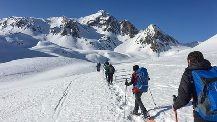 In winter, some hikers walk the snowy valley at the Lucomanio pass in Switzerland.