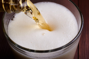 Pouring beer with foam into a glass.