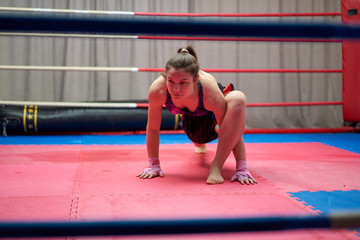 Female kickboxer stretching in the ring