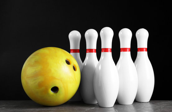 Yellow bowling ball and pins on grey stone table
