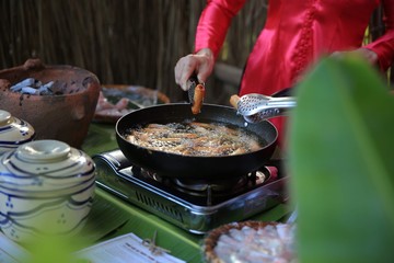 A young lady wearing red dress preparing food on a cooking bowl
