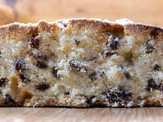 Delicious, delicious raisin cake sprinkled with icing sugar, cut on a wooden table. New Year, Christmas, Easter muffins and other holiday dough products.