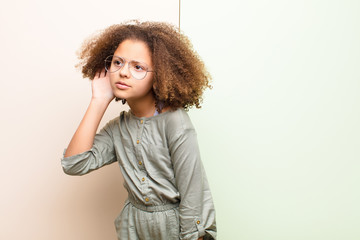 african american little girl looking serious and curious, listening, trying to hear a secret...