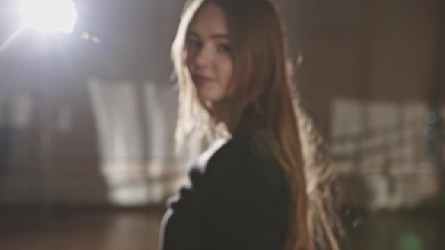 Tilt down view of exhausted young woman looking at camera then turning around and walking away during dancing training in studio