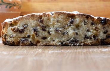 Delicious, delicious raisin cake sprinkled with icing sugar, cut on a wooden table. New Year, Christmas, Easter muffins and other holiday dough products.