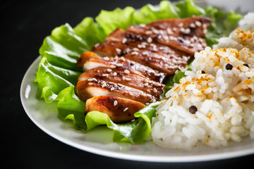 Homemade food - teriyaki chicken with white rice and pepper on a black background.