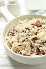 Delicious rice pilaf with mushrooms on white wooden table, closeup