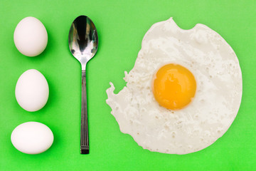 White eggs and spoon on a green background. Breakfast concept, soft-boiled egg. International cuisine, food. Top view, copy space.