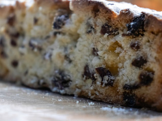 Delicious, delicious raisin cake sprinkled with icing sugar, cut on a wooden table. New Year, Christmas, Easter muffins and other holiday dough products.