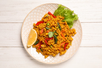 Delicious rice pilaf with vegetables on white wooden table, top view