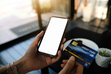 Woman's hands holding smartphone with blank screen and credit card,internet banking, online trading, e commerce concept.