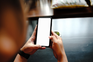 Mockup image of a man holding mobile phone with blank black screen in modern loft cafe