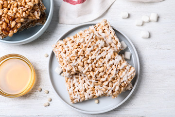 Delicious rice crispy treats on white wooden table, flat lay