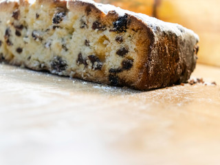 Delicious, delicious raisin cake sprinkled with icing sugar, cut on a wooden table. New Year, Christmas, Easter muffins and other holiday dough products.