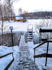 Stairs for swimming in an ice hole on the lake after a sauna on a cold day.