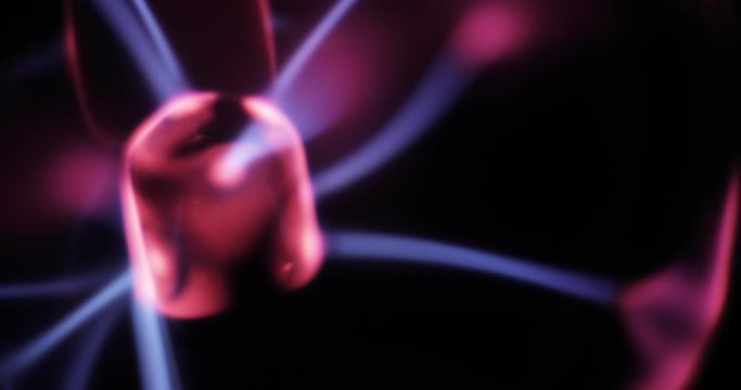 Closeup view of tesla plasma ball in center with pink and blue lightnings in dark. Tesla coil experiment with electricity, glowing plasma lamp. Electrode and gas inside ball.