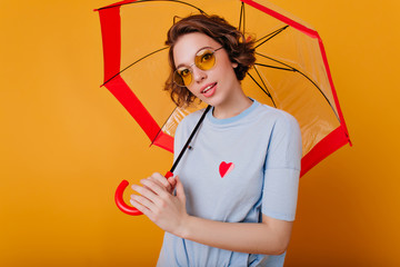 Indoor portrait of pretty girl in blue shirt holding parasol. Photo of wonderful caucasian lady...
