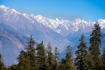Amazing view of snow clad mountain landscape surrounded by dense forest during Kedarkantha winter trek in Uttarkashi, Uttarakhand (India). Trek in December on Christmas and New Year