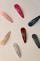 Fashionable colorful hair clips on pale background. Flat lay.