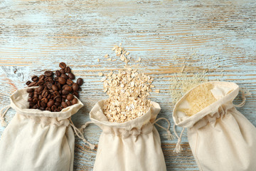Cotton eco bags with cereals and coffee beans on wooden table, flat lay