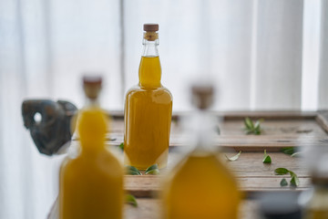 detail of bottles filled with golden liquid oil juice healthy organic fresh wellness body on a wooden mediterranean piece of furniture sharp unsharp stylish