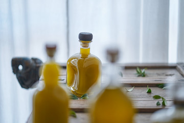 closeup of bottles filled with golden liquid oil juice healthy organic fresh on a wooden mediterranean piece of furniture sharp unsharp stylish