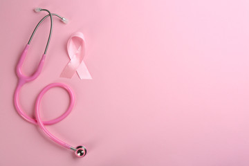 Fototapeta premium Pink ribbon as breast cancer awareness symbol and stethoscope on color background, flat lay. Space for text